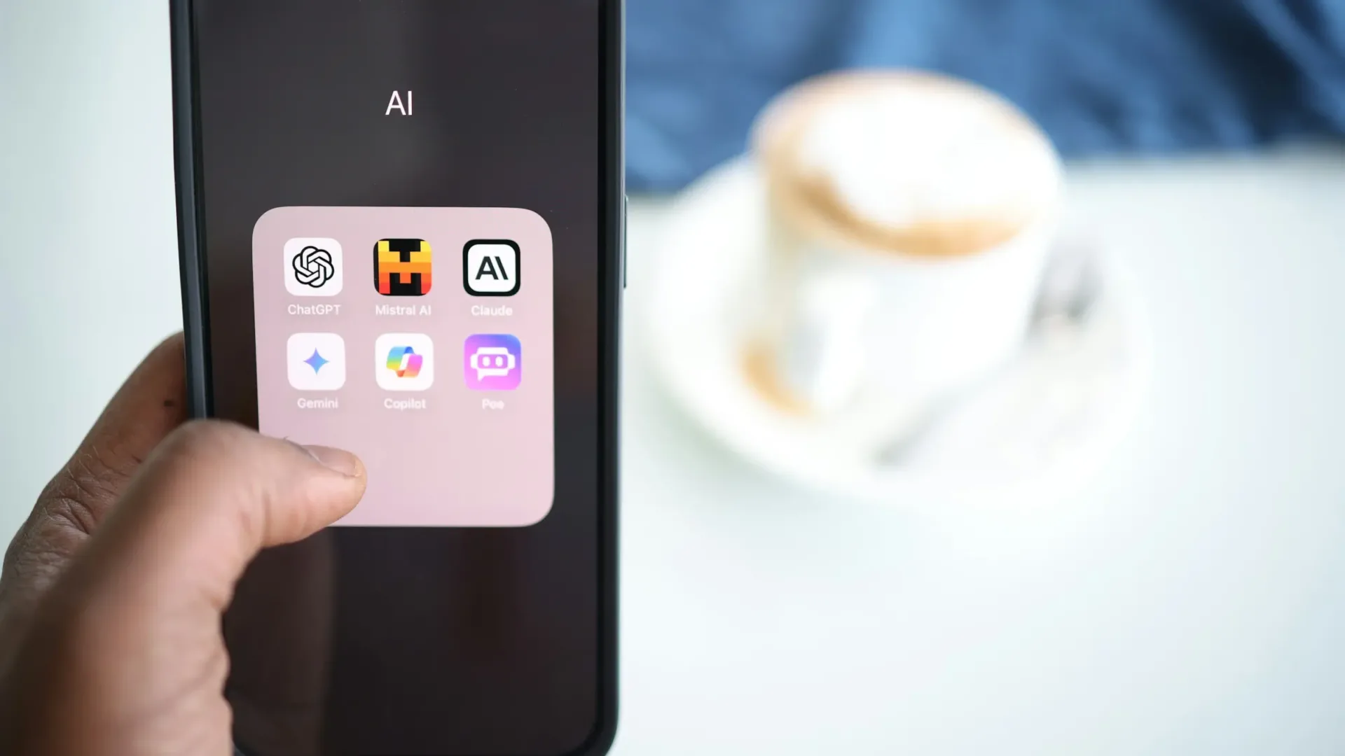 Hand holding a phone displaying multiple AI apps on the screen