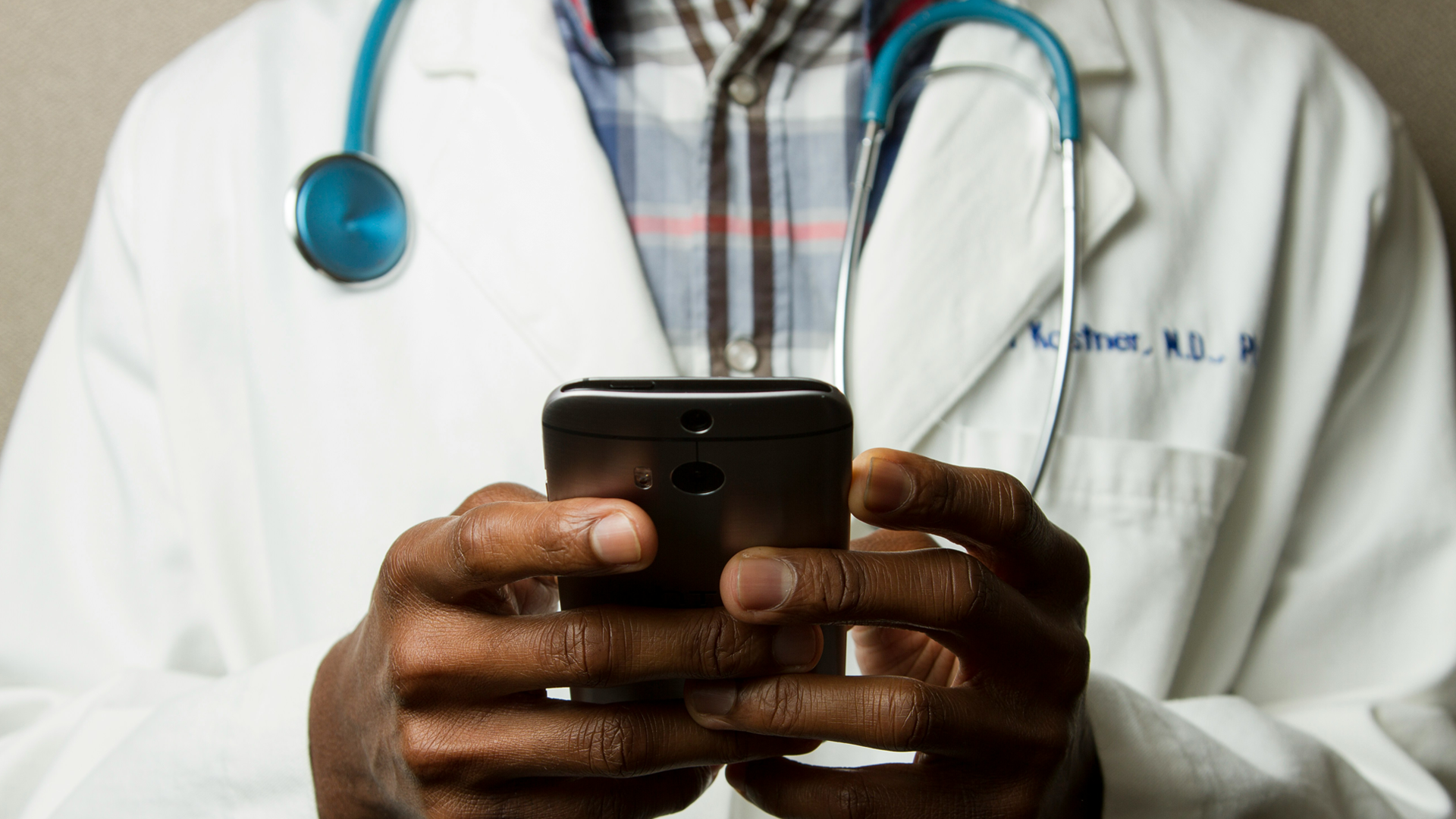 Closeup of a healthcare provider holding a phone using Q-Rounds, an MVP prototype designed by Clockwork.